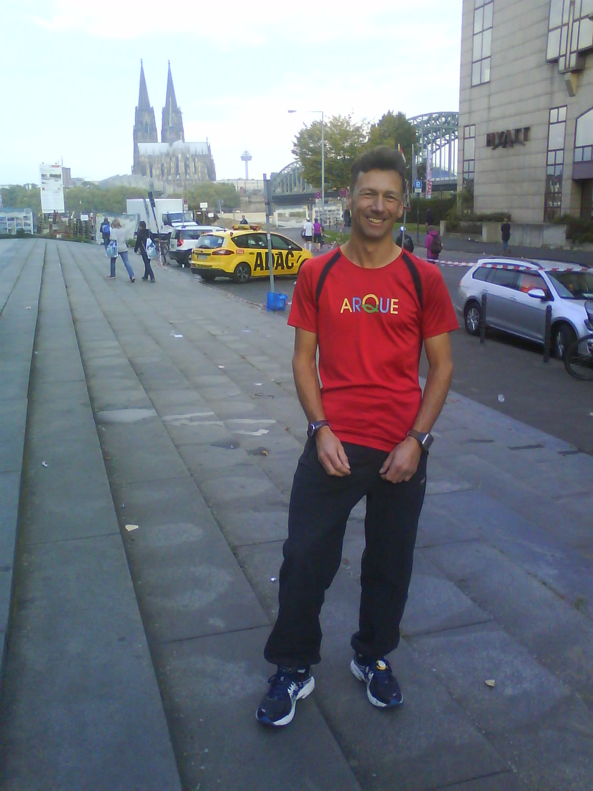 Arno Wenzel mit ARQUE-Shirt, im Hintergrund der Kölner Dom