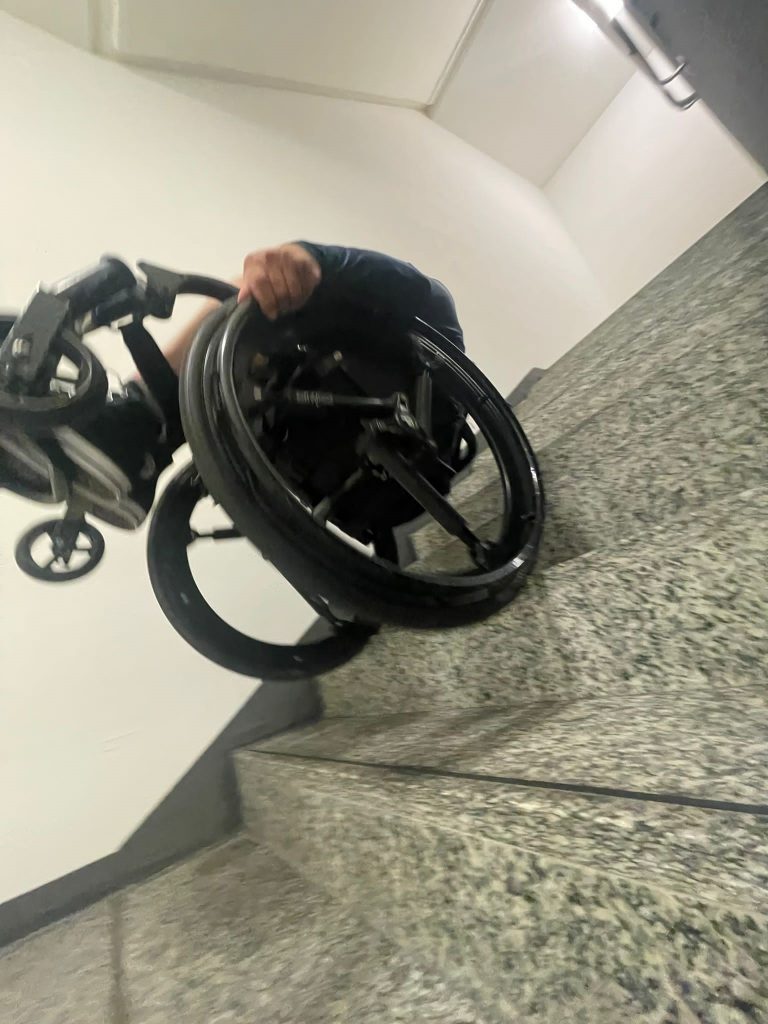 Haki Doku auf der Treppe im Rollstuhl, Bild zeigt Bewegungsunschärfe beim Treppenabstieg.